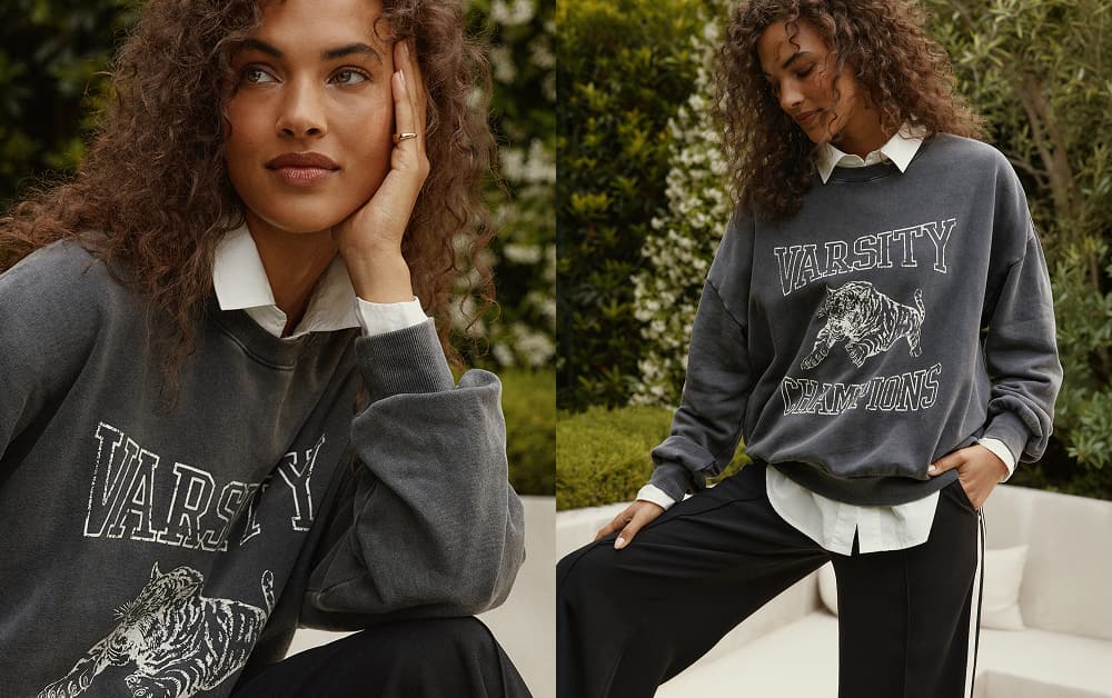 Image of woman wearing grey graphic sweatshirt and track pants