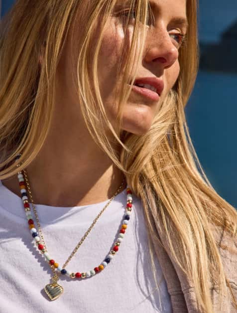 Image of woman wearing a colorful beaded necklace with a gold heart pendant necklace