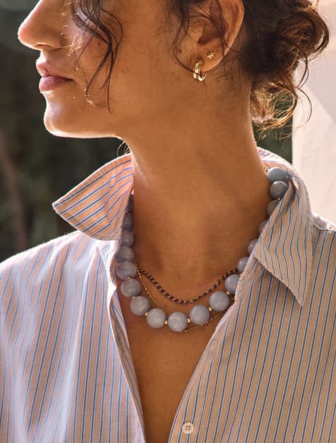 Image of woman wearing a light blue beaded Vida necklace with a button down shirt
