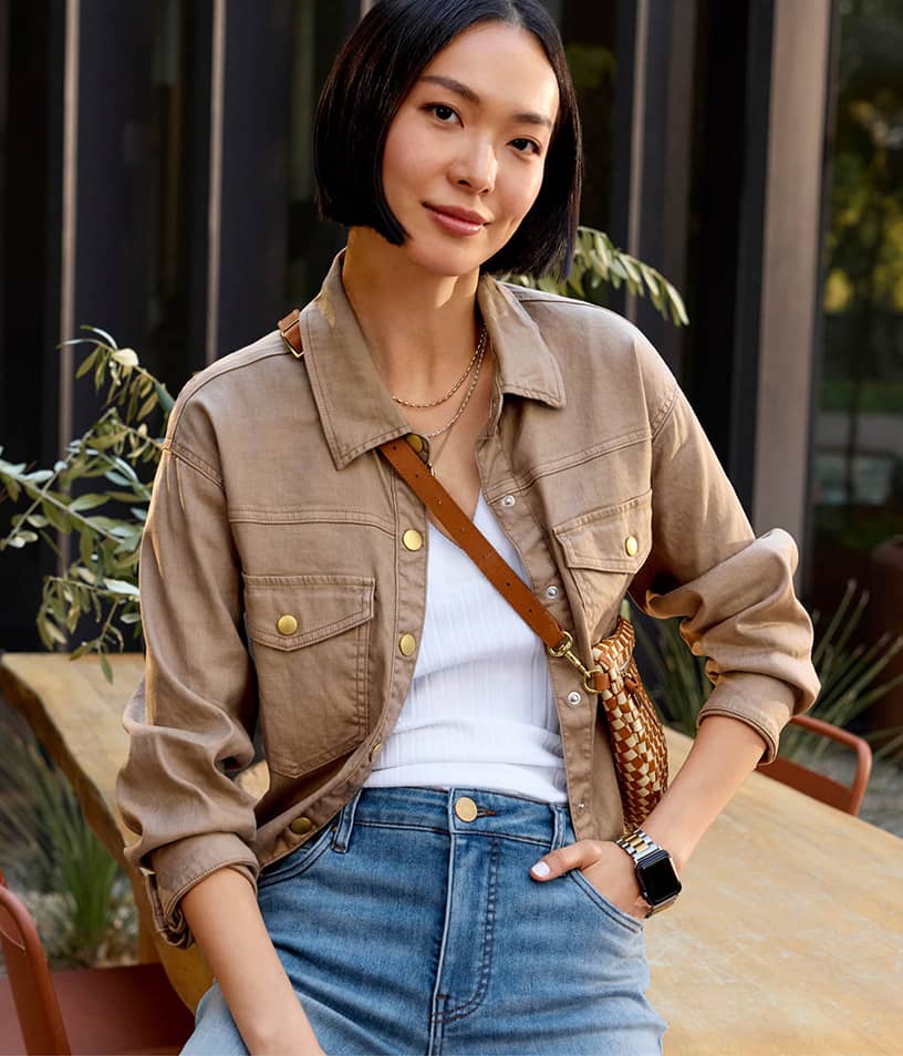 Image of woman in a khaki button front jacket with blue jeans and a white tee