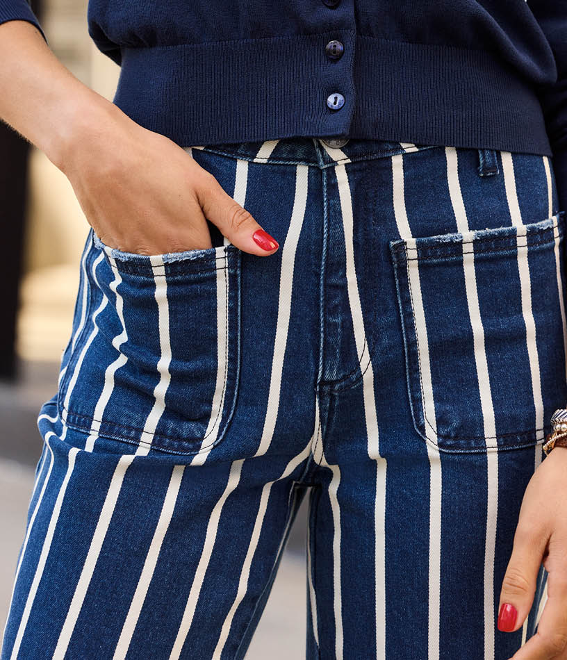 Image of a woman wearing blue and white stripe jeans with her hand in her pocket