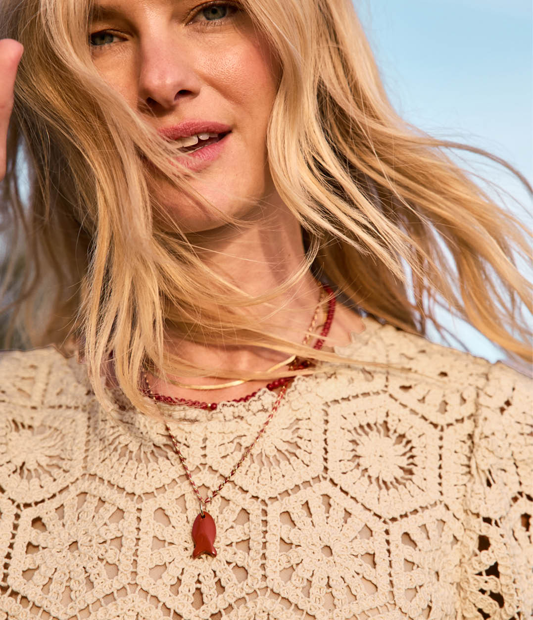 Image of woman wearing an ivory lace top with necklace