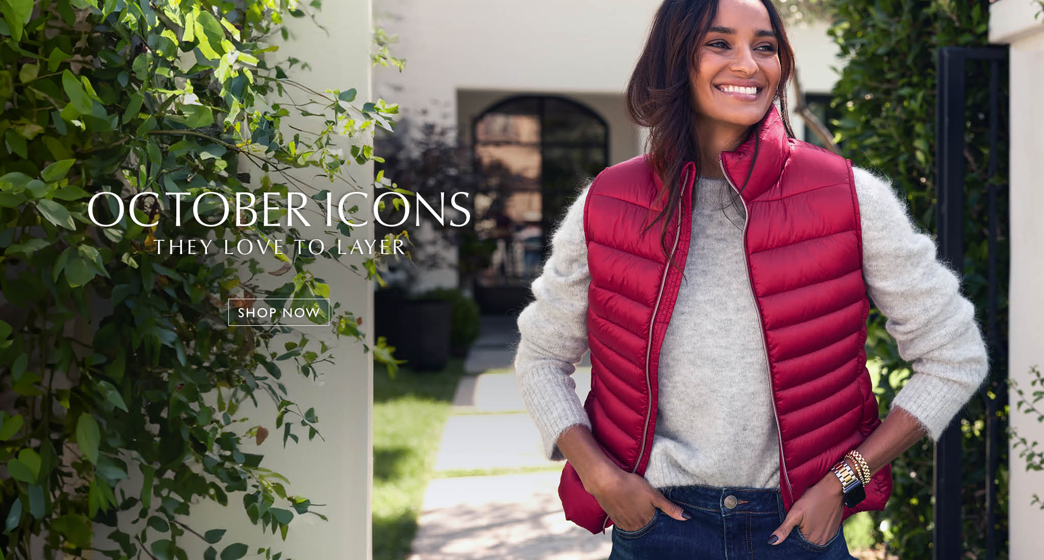 Women wearing grey sweater with red puffer vest. Text over the image reads “October icons. They Love to Layer. Shop now