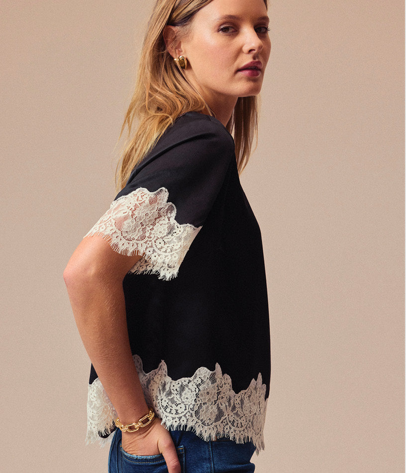 Image of woman wearing black satin blouse with ivory lace trim