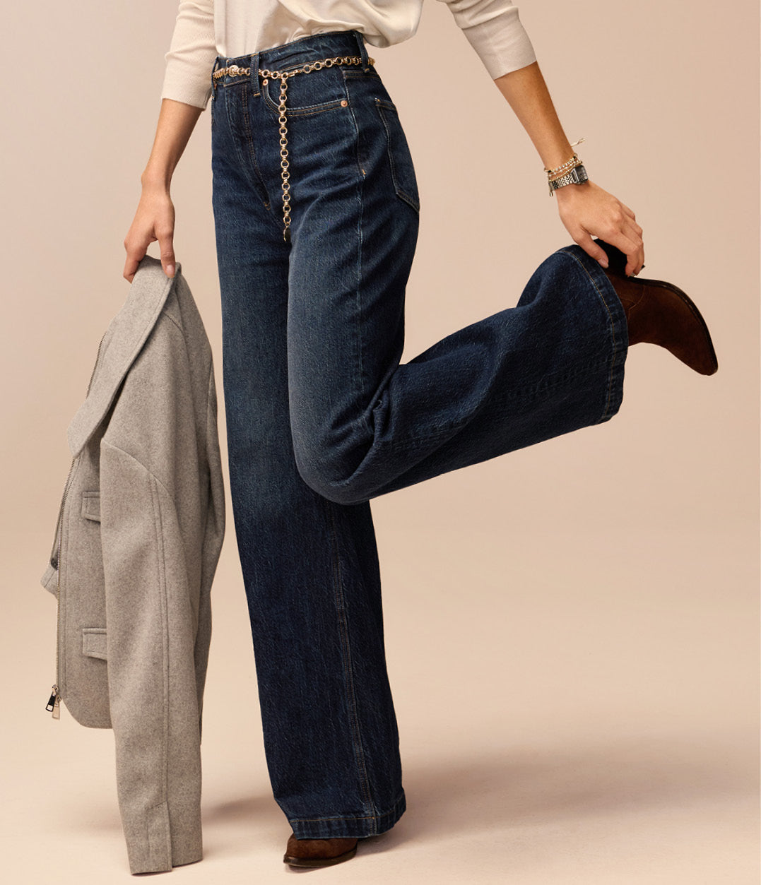 Image of woman wearing dark blue wide leg jeans with metal chain belt