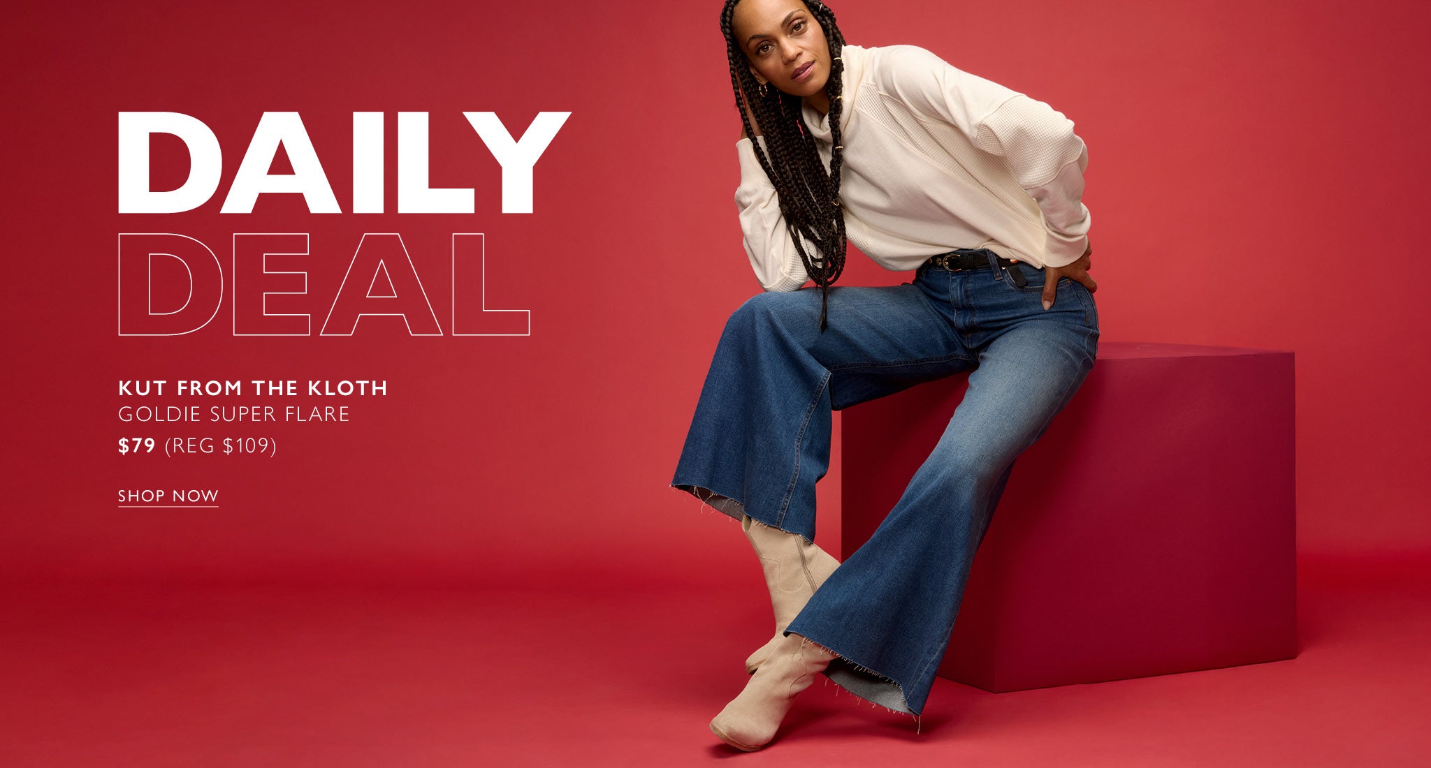 Woman wears wide leg blue jeans with a black studded belt and an ivory sweatshirt. Text over image reads: Daily Deal, Kut From The Kloth Goldie Super Flare $79 (Reg $109), Shop Now