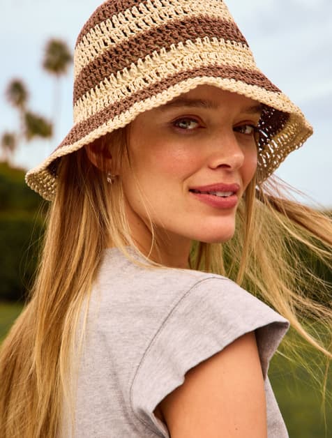 Image of woman wearing a striped raffia bucket hat
