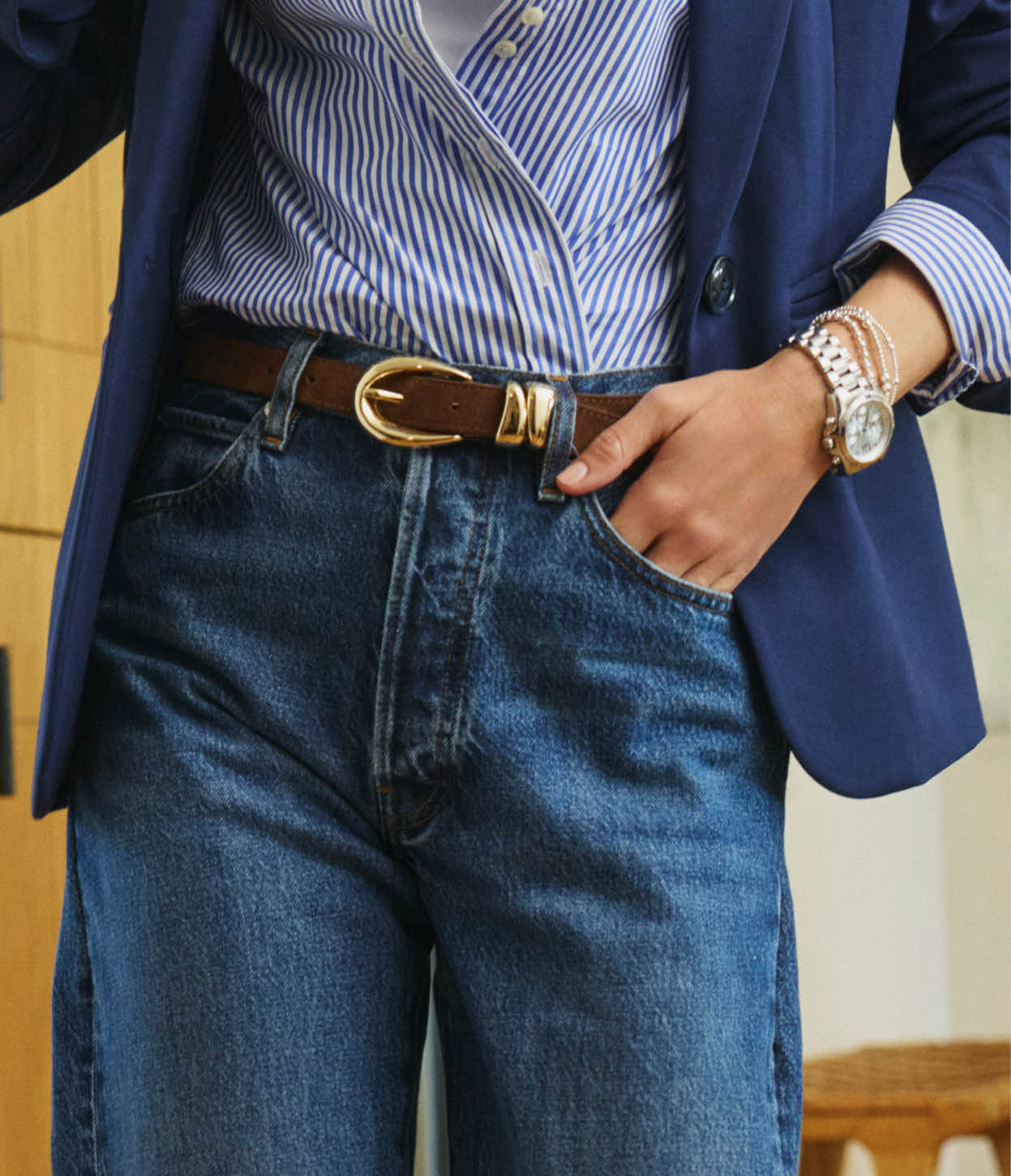 Image of woman wearing jeans with a stripe button-down shirt and brown belt