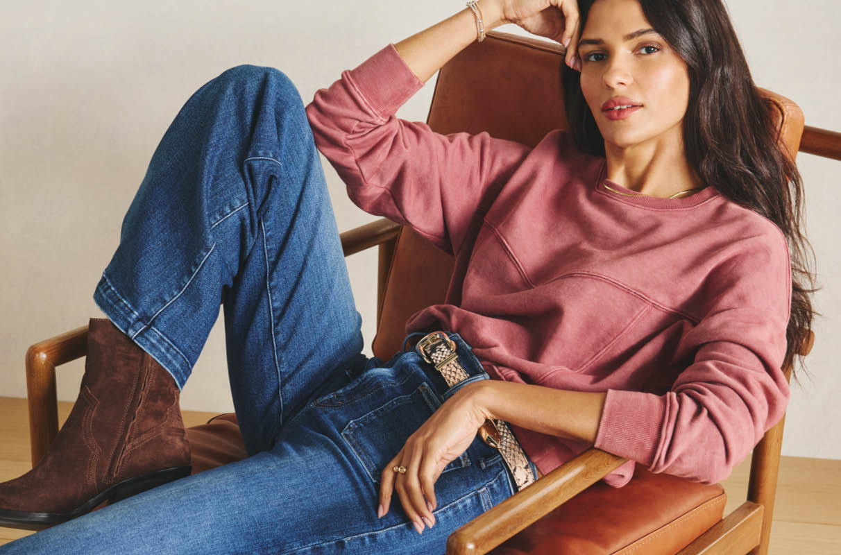 Image of woman wearing a pink sweatshirt with blue jeans and brown boots