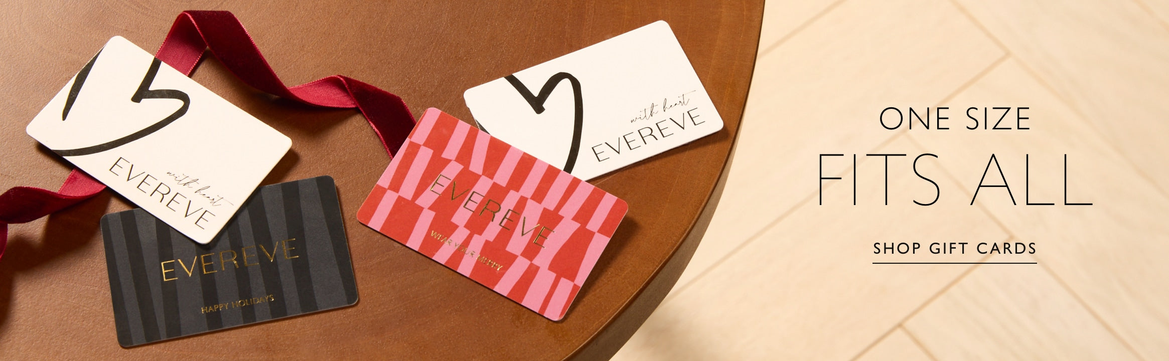 Several EVEREVE gift cards on a wooden table. Text over image reads: "One size fits all, Shop gift cards". 