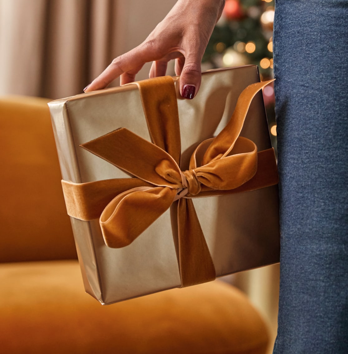 Image of a gold foil wrapped gift box with a gold velvet bow.