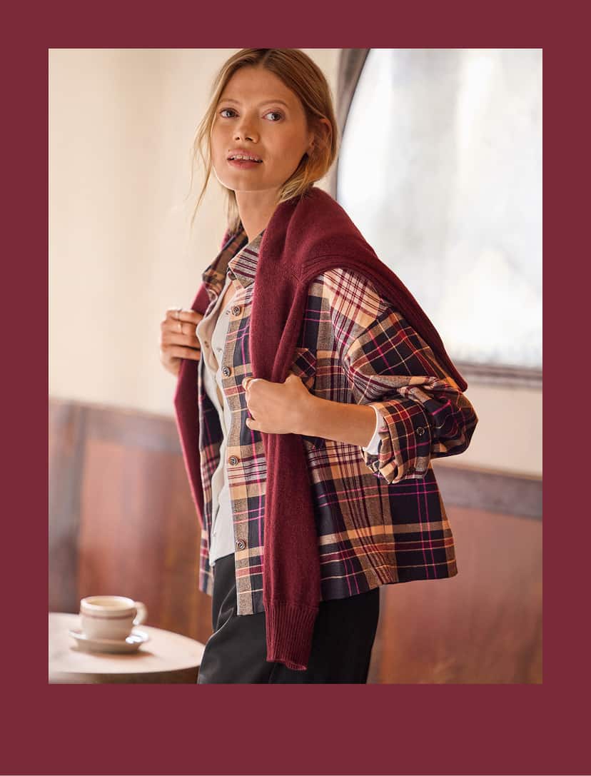 Woman wearing a plaid button down shirt over a white tee and black wide leg pants. 
