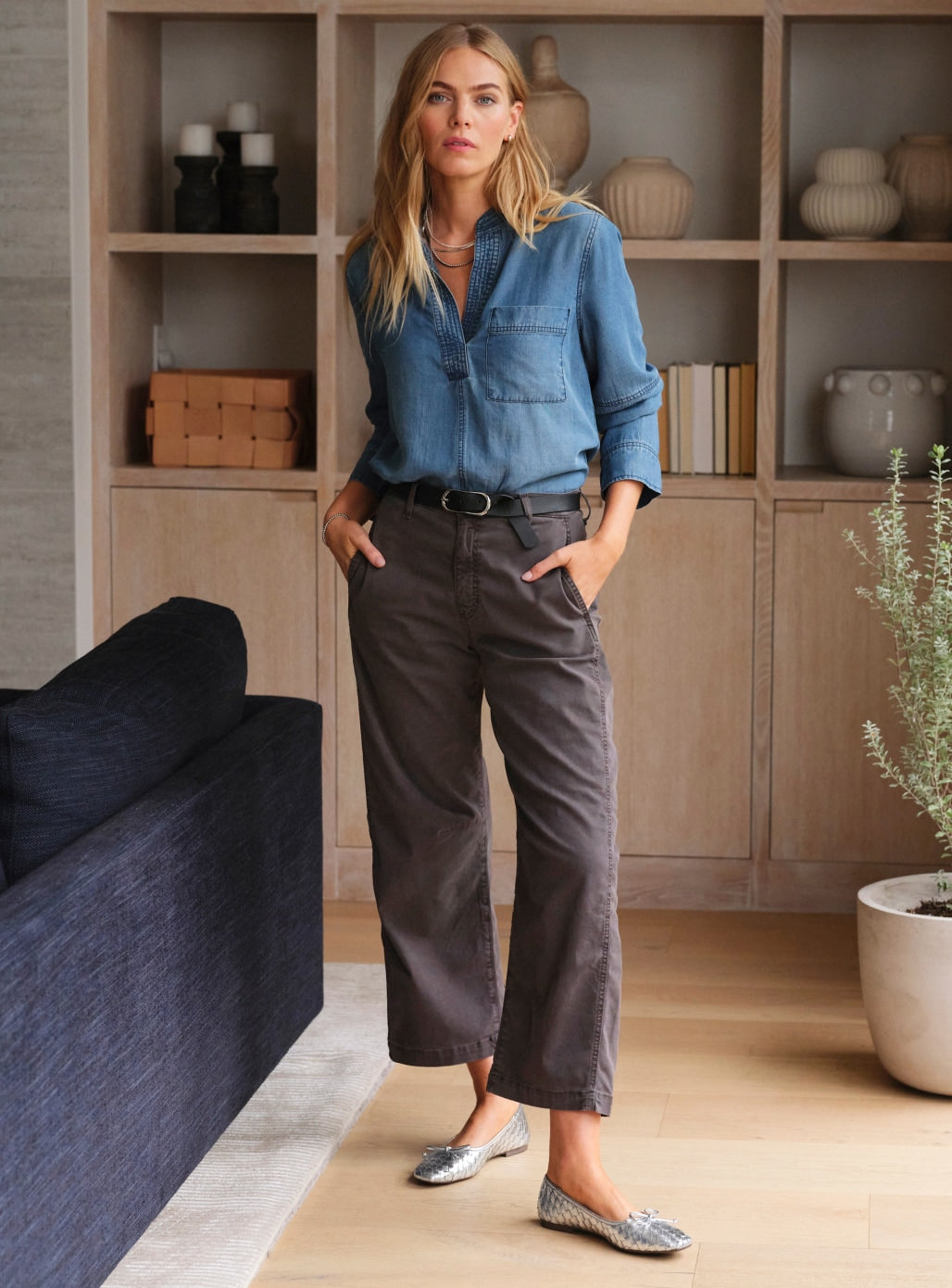 Image of woman wearing blue shirt, brown pants, and silver flats.