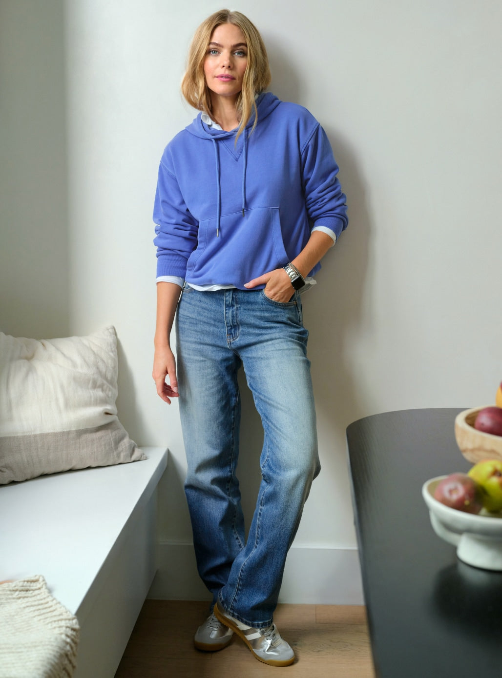 Image of woman wearing a blue hoodie with blue jeans and silver sneakers.