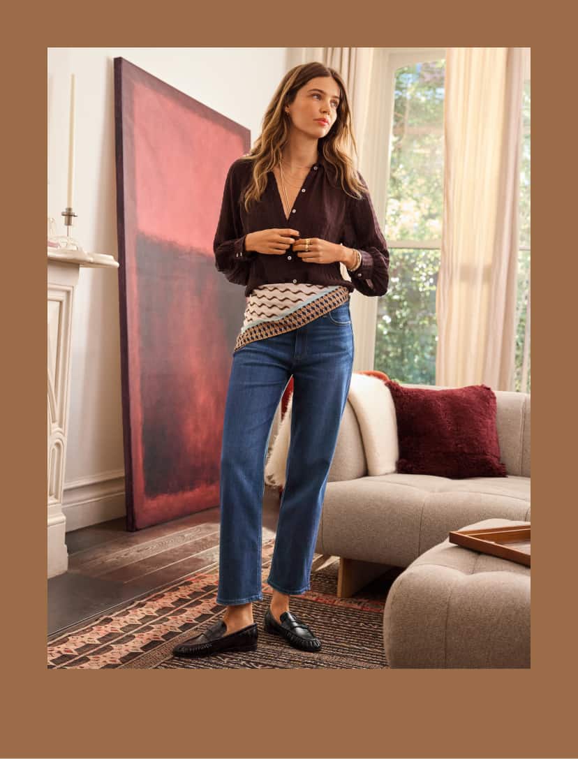 Woman wearing a brown poet blouse with blue Paige jeans and a scarf tied at her waist. 