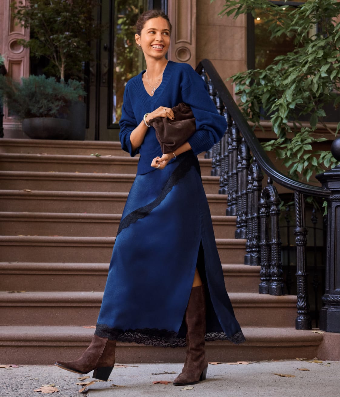 Woman wearing blue vneck sweater with blue satin skirt with black lace trim.