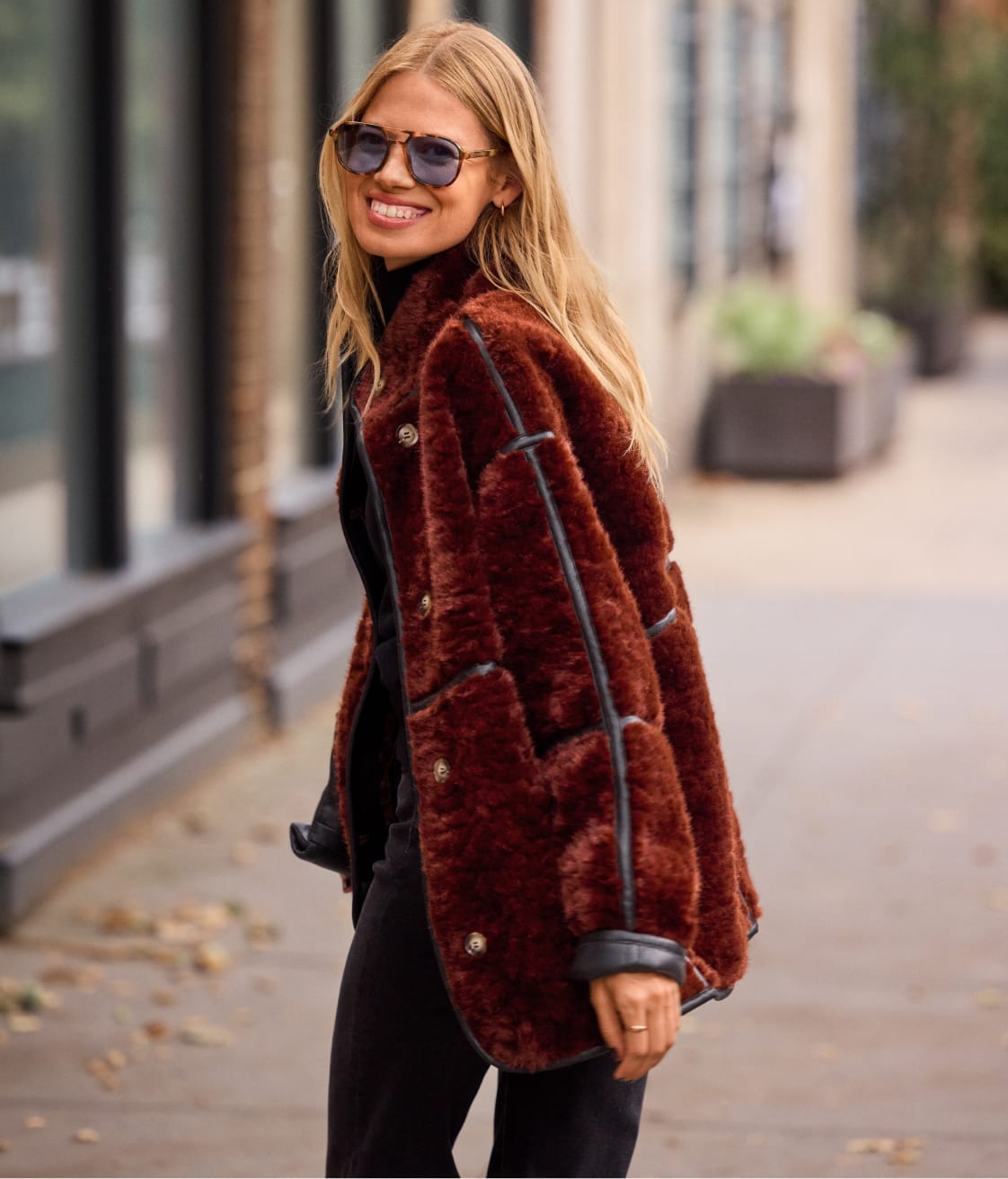 Woman wearing red faux fur jacket with black leather trim 
