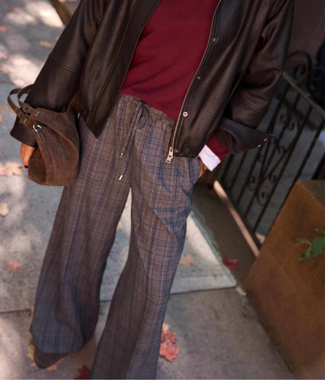 Woman wearing plaid pull on pants with a burgundy sweater and leather jacket. 