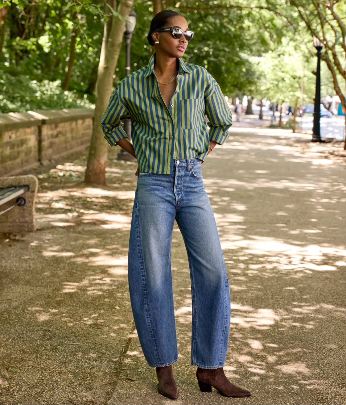 Woman wearing gren striped button down shirt with barrel leg blue jeans and brown boots.