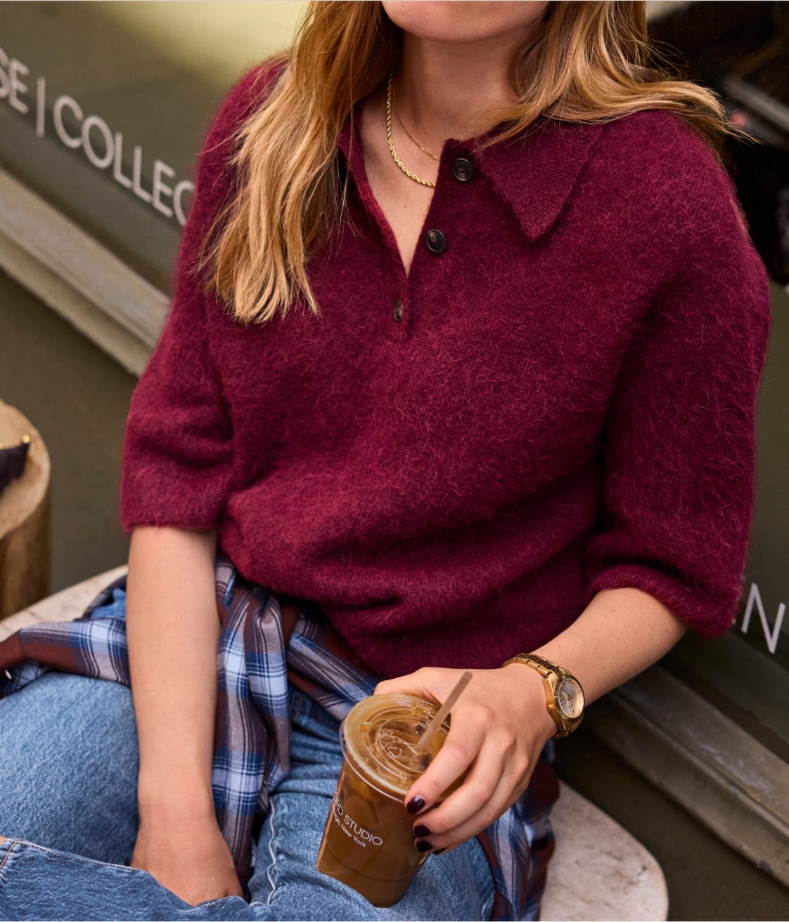 Woman wearing a burgundy polo style sweater with short sleeves. 