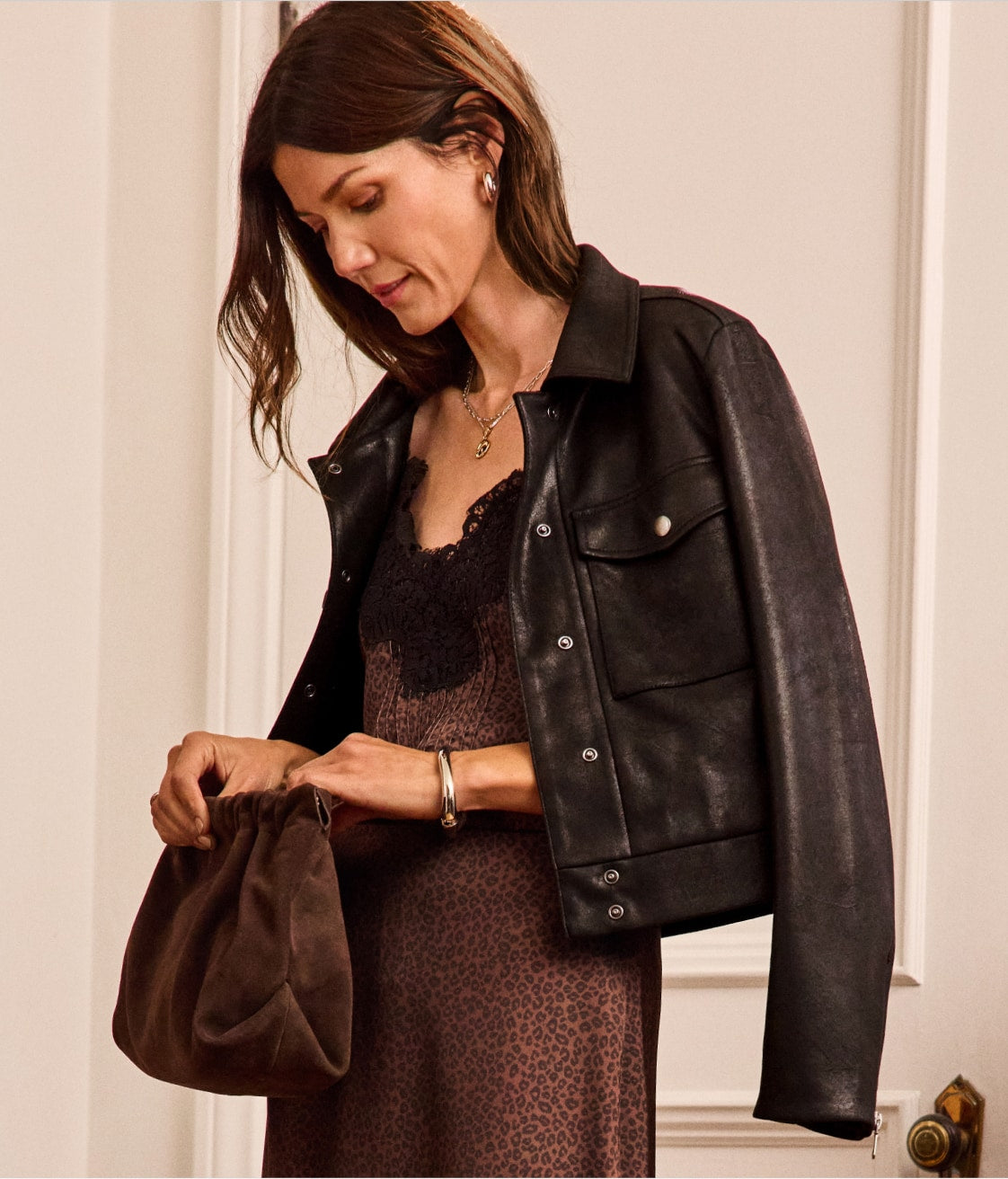 Woman wearing an animal print slip dress with a black leather jacket on her shoulders.