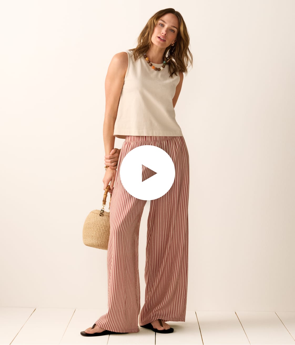 Image of woman wearing a cream tank with red and cream stripe wide leg pants. 