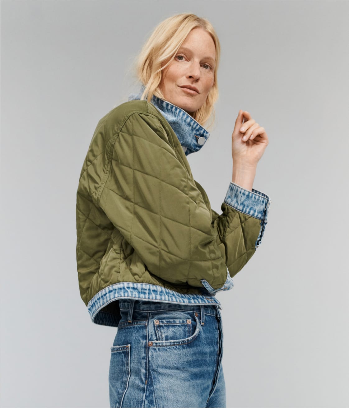 Woman wearing olive quilted jacket with blue jeans