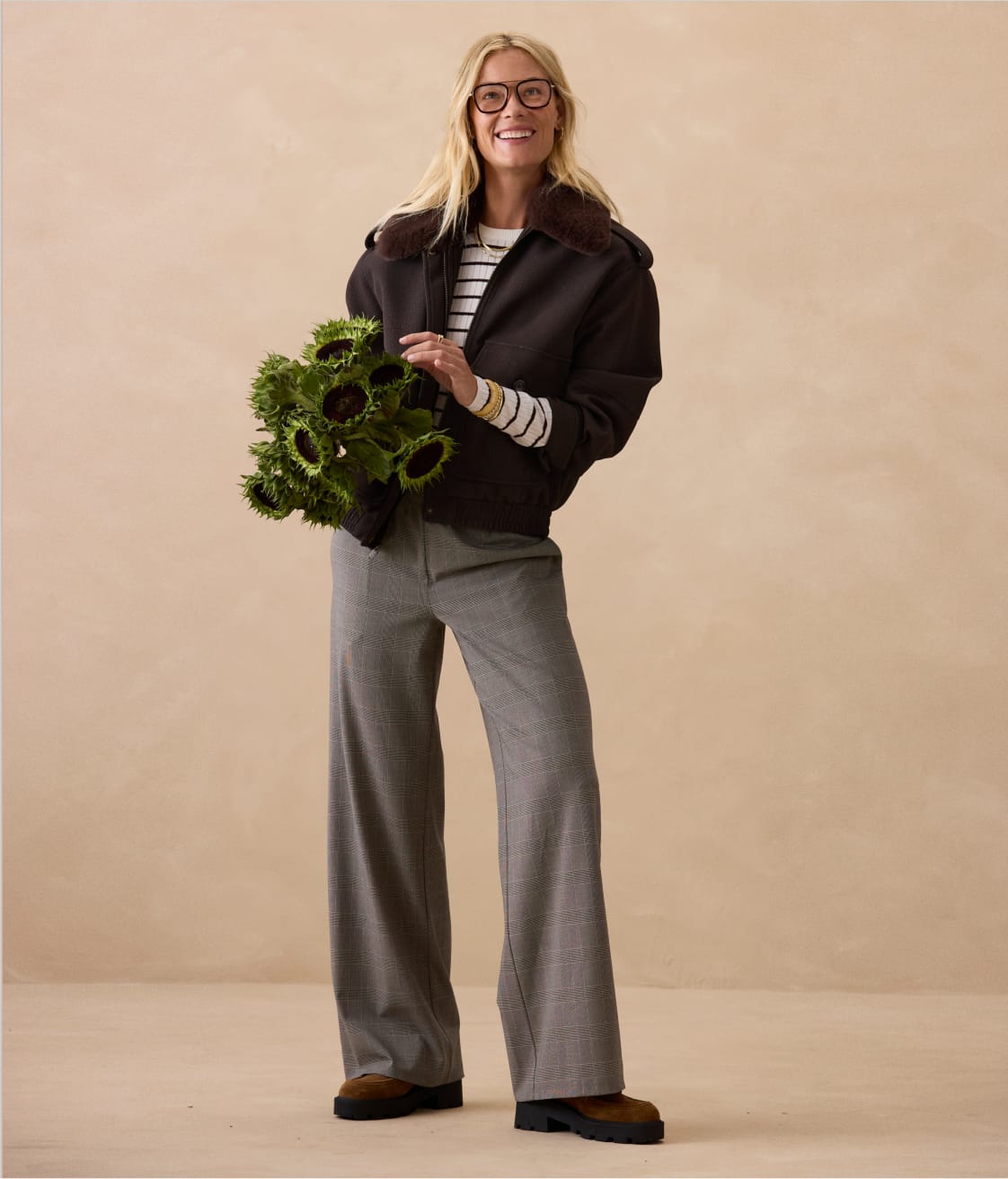 Woman wearing black jacket over a stripe top and wide leg grey trousers