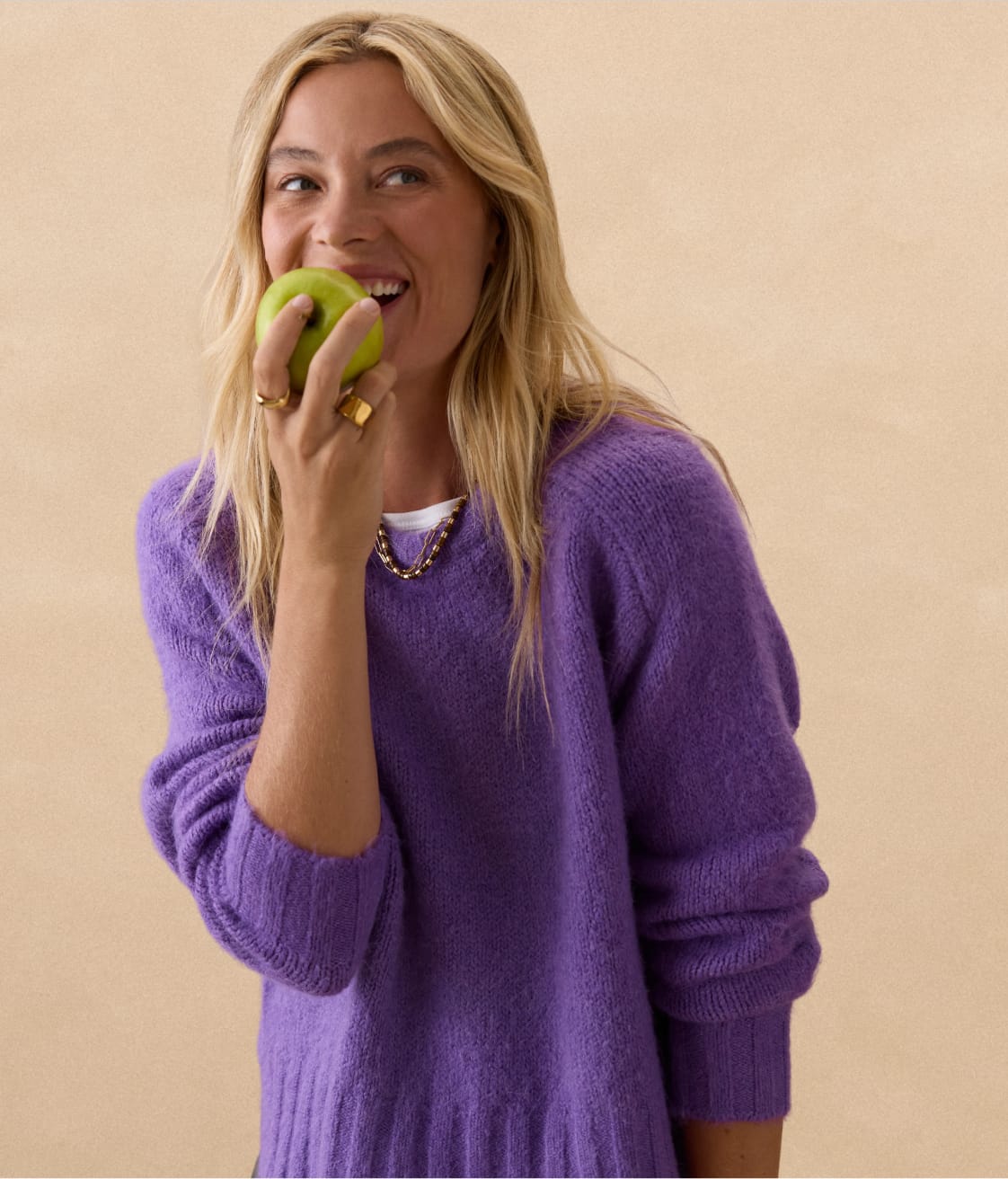 Woman wearing a purple fishermans sweater over a white tee with a beaded necklace