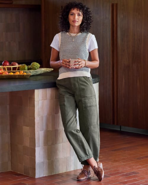 Image of woman wearing a white tee with a sweater vest and utility pants