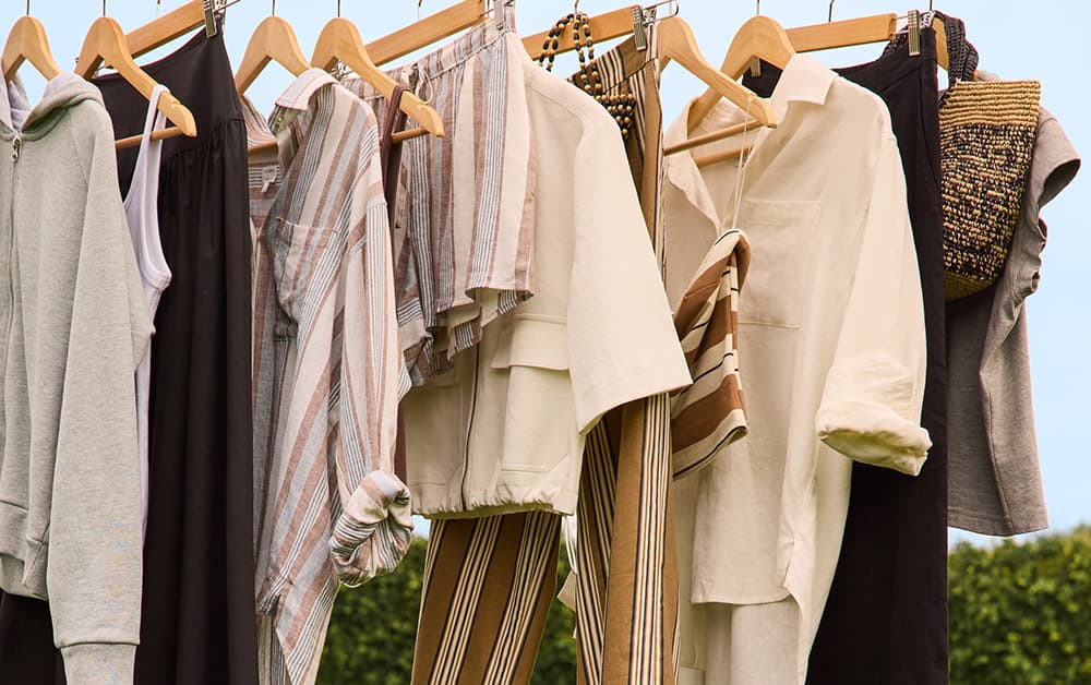 Image of everyday icons tops, button-downs, shorts, and pants hanging on hangers