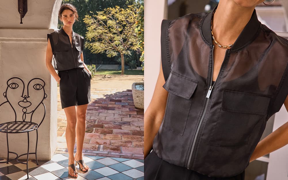 Image of woman wearing a sheet black zip up jacket over a tank and black skirt